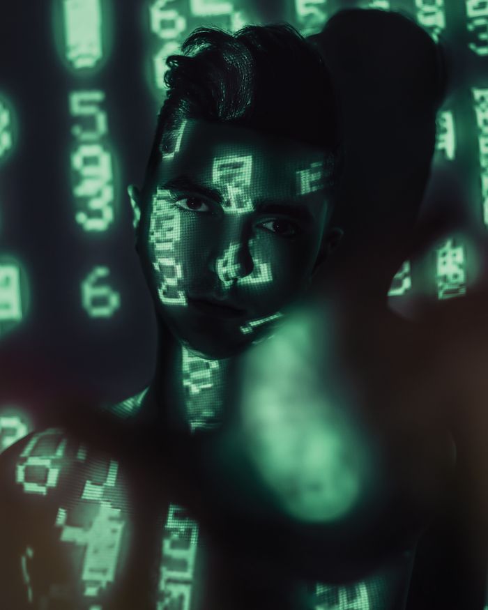 Creative portrait of a man with green digital numbers projected onto his body, evoking a tech-inspired aesthetic.