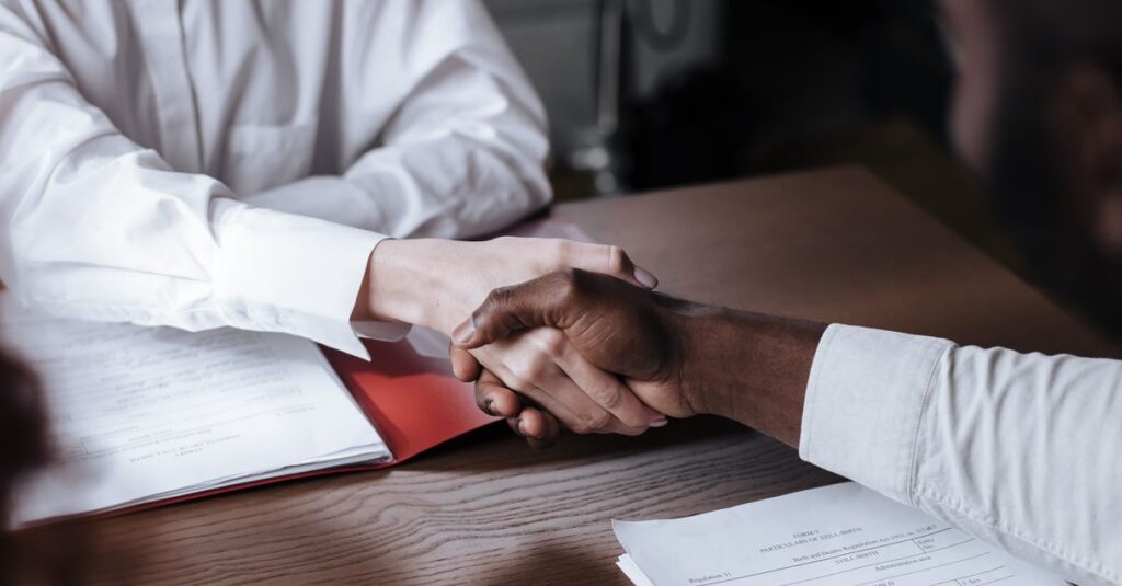 Close-up of a diverse business handshake over documents, symbolizing agreement and collaboration.